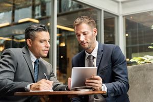 Two businessmen wearing suit having a business meeting